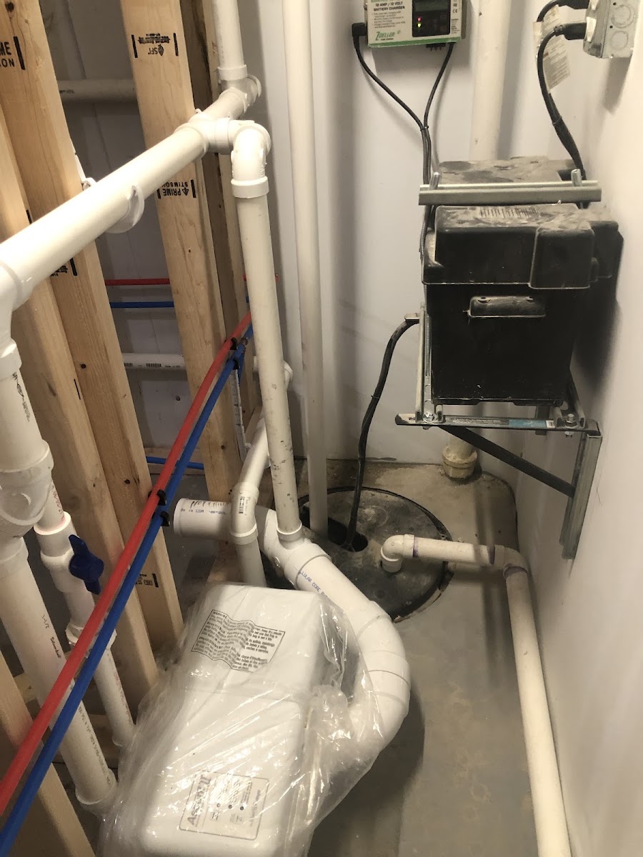 Basement plumbing rough-in with PEX lines and a battery-backup sump pump system